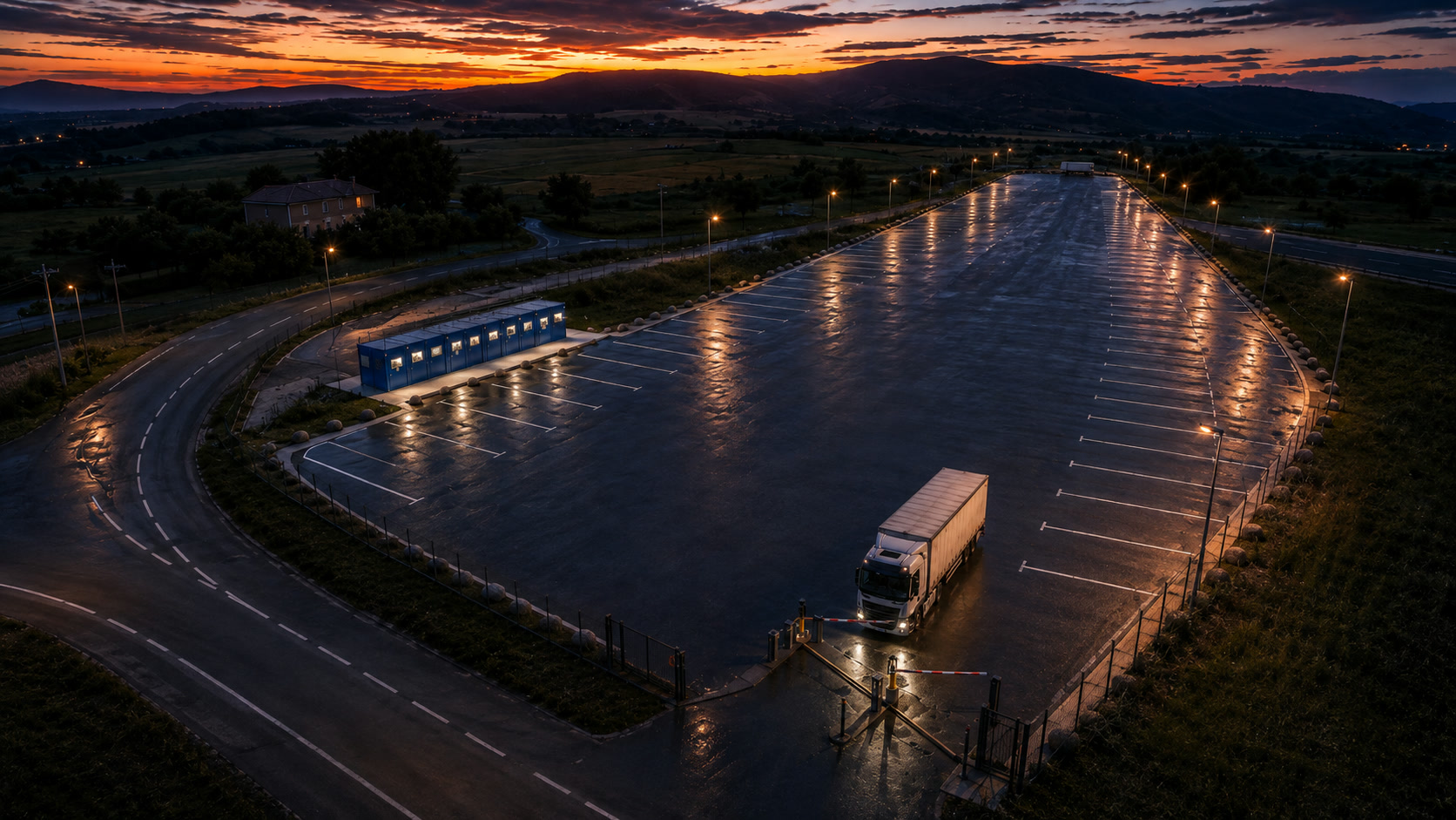L'area di sosta Il Ruzzolone vista dall'alto al tramonto, con il piazzale illuminato e un camion in ingresso
